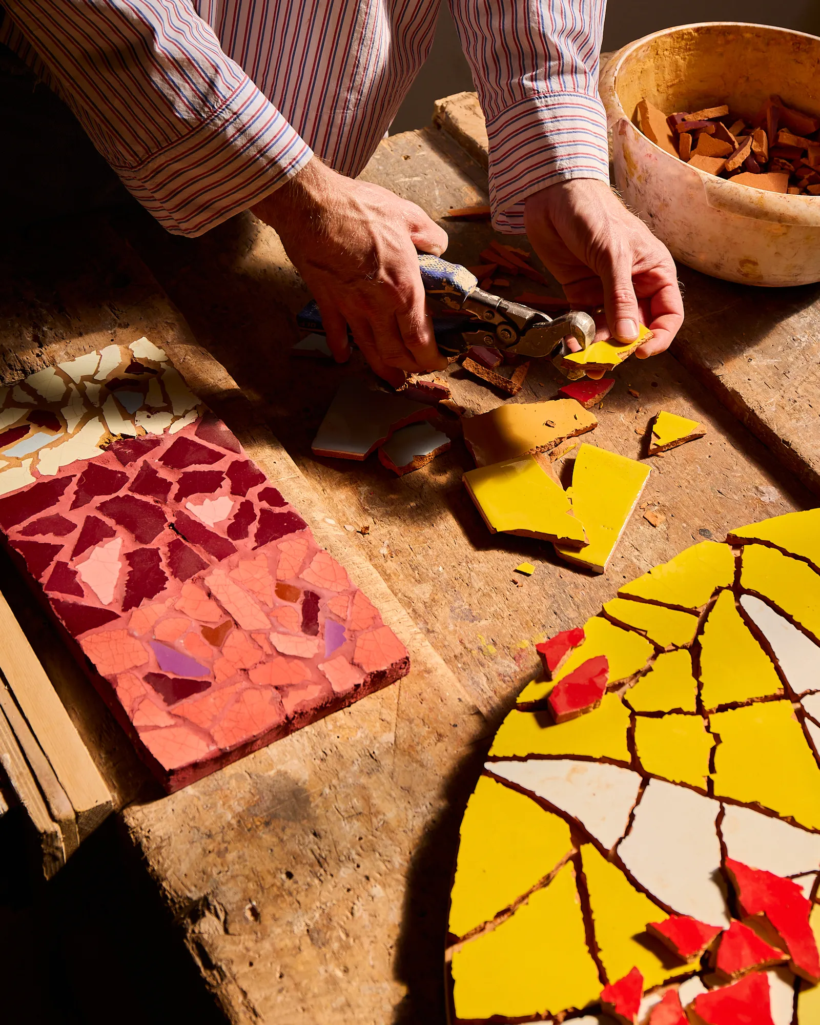 Everywhere there are clues to Charlie's process. Piles of broken tiles wait patiently to become flowers, leaves and suns.