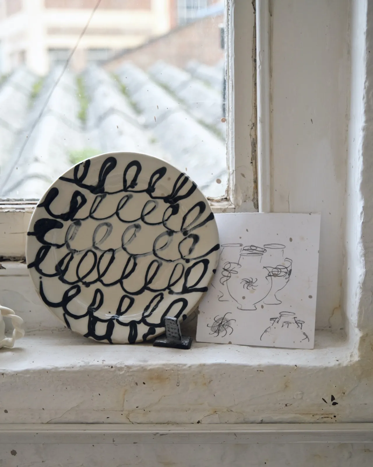 A sliptrailed plate sits slongside drawn designs for caudle cups